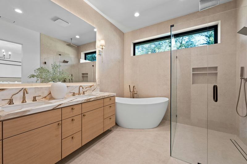 Bathroom with a wood double vanity, freestanding tub, and glass shower