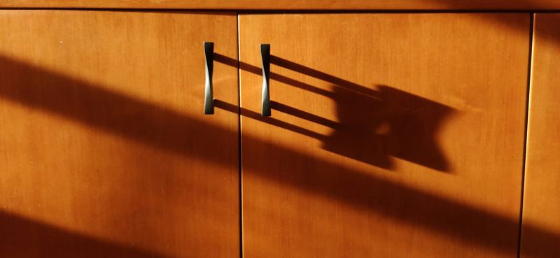 Warm wood cabinet doors with slim metal pulls in afternoon light